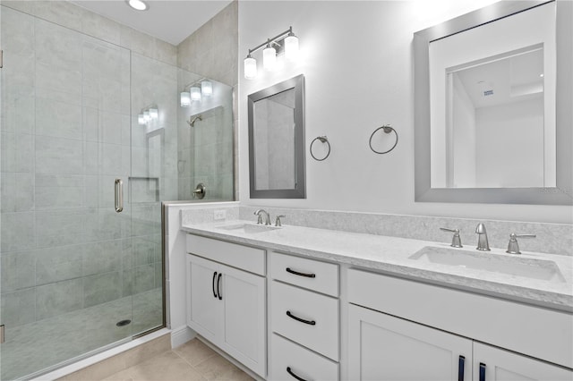 bathroom with a shower with door, tile flooring, oversized vanity, and dual sinks