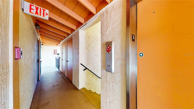 hallway with vaulted ceiling with beams and concrete flooring