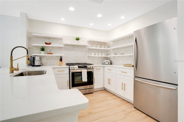 kitchen with stainless steel appliances, white cabinets, sink, and light wood-type flooring