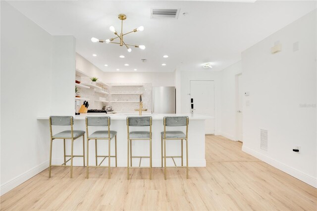 kitchen featuring kitchen peninsula, light hardwood / wood-style floors, and a breakfast bar area