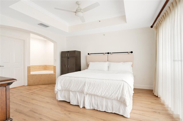 bedroom featuring light wood-type flooring, ceiling fan, and a raised ceiling