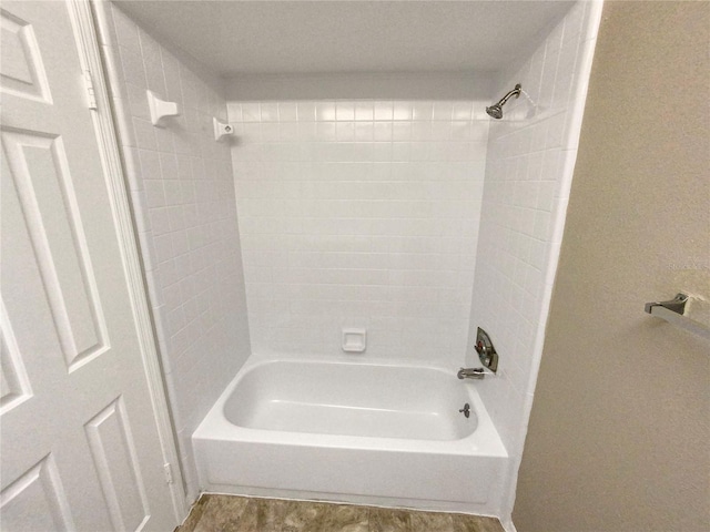 bathroom featuring a textured ceiling and tiled shower / bath