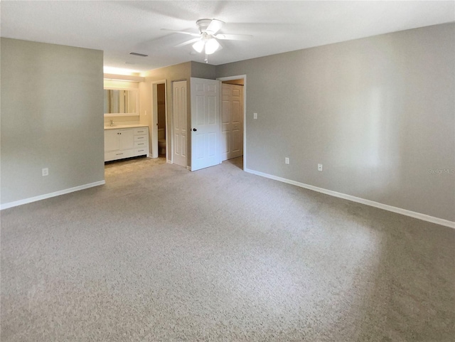 interior space featuring carpet, ensuite bathroom, and ceiling fan