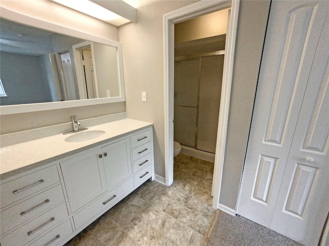 bathroom with tile floors, a shower with door, vanity, and toilet