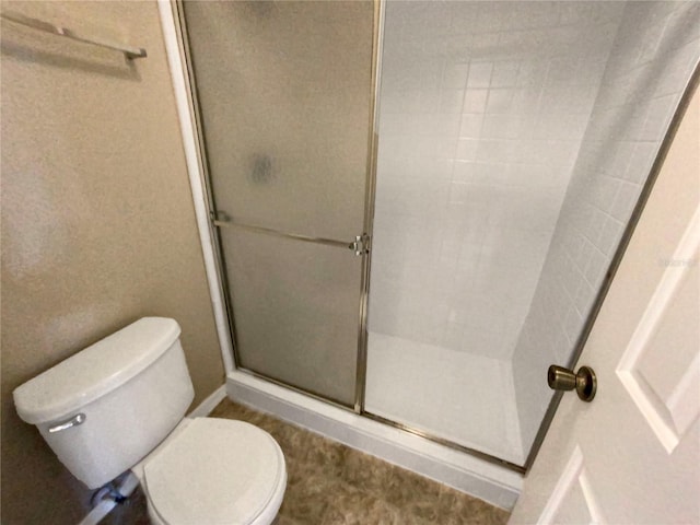 bathroom with a shower with shower door and toilet