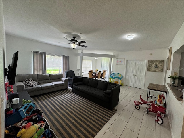 living room with ceiling fan and a textured ceiling