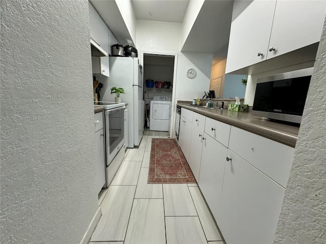 kitchen with sink, white cabinetry, washer and clothes dryer, and electric stove