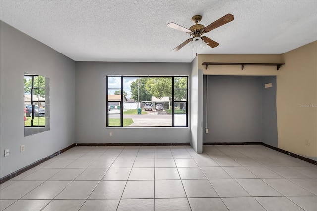 unfurnished room with plenty of natural light, a textured ceiling, light tile flooring, and ceiling fan