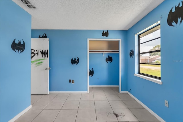 tiled empty room featuring a textured ceiling