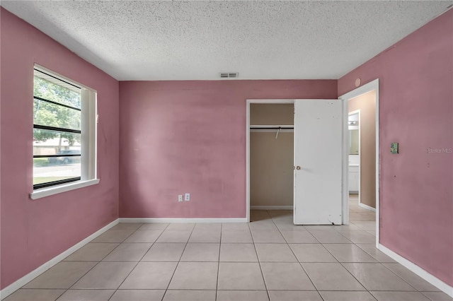 unfurnished bedroom with a textured ceiling, a closet, and light tile floors