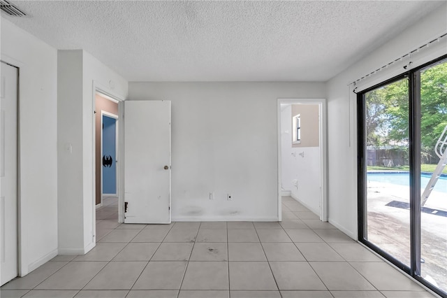 tiled spare room featuring a textured ceiling