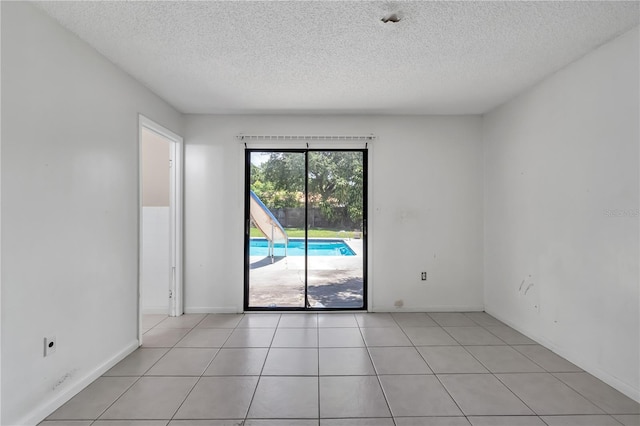 spare room featuring light tile flooring and a textured ceiling