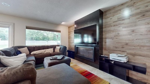 living room with a large fireplace, plenty of natural light, and wooden walls