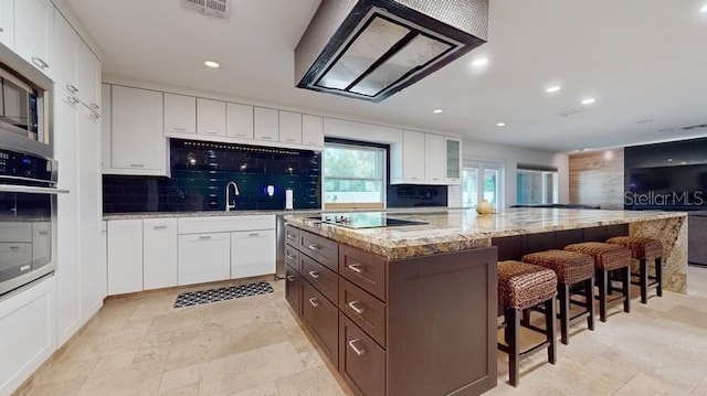 kitchen featuring backsplash, white cabinets, a center island, and dark brown cabinets