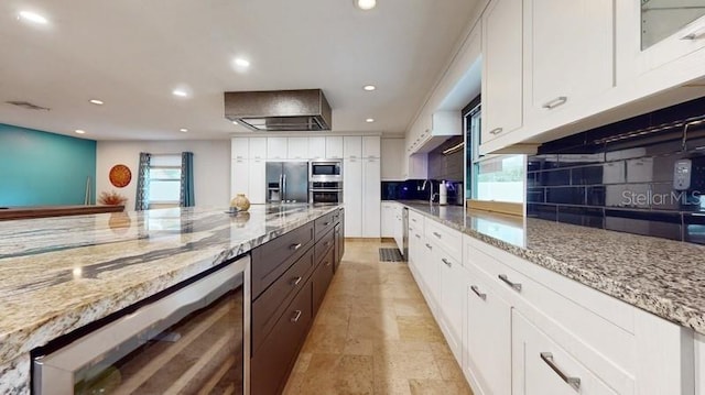 kitchen featuring white cabinetry, light stone countertops, appliances with stainless steel finishes, tasteful backsplash, and light tile floors