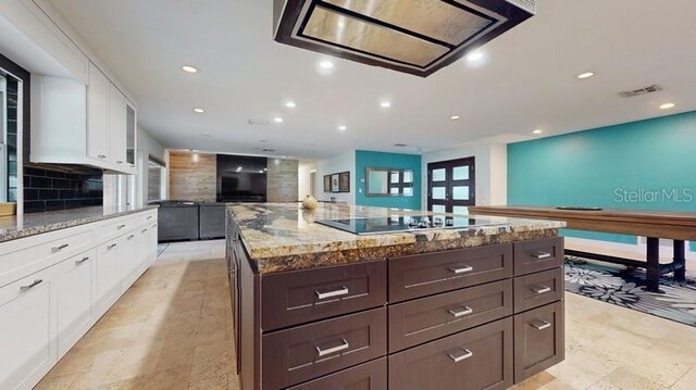 kitchen with white cabinetry, black electric stovetop, light stone counters, backsplash, and light tile floors