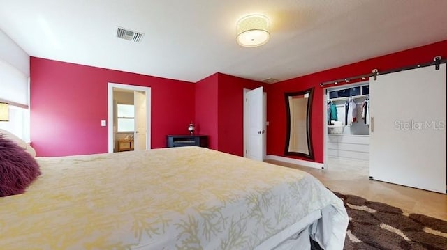 bedroom featuring a barn door, a closet, and connected bathroom