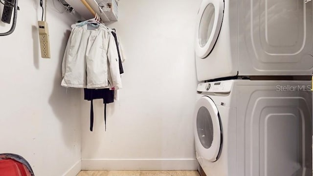 laundry area with light tile flooring and stacked washer / drying machine