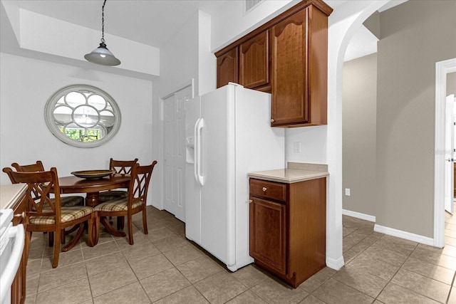 kitchen with white refrigerator with ice dispenser, pendant lighting, range, and light tile patterned floors