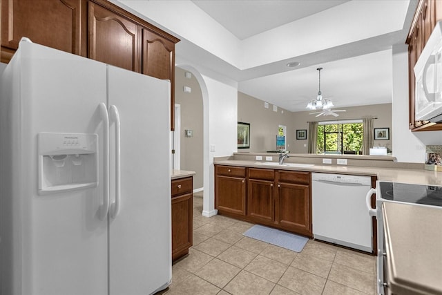 kitchen featuring sink, white appliances, light tile patterned floors, and kitchen peninsula