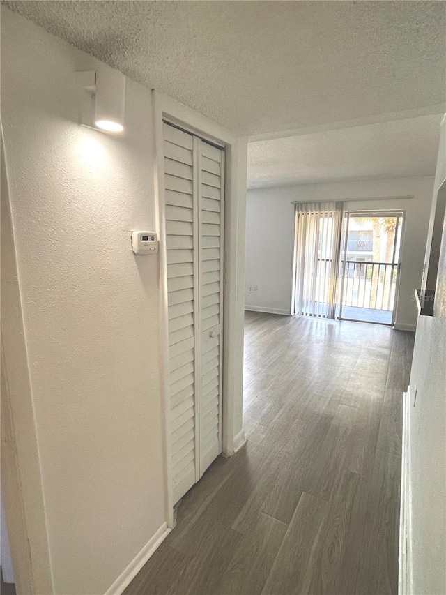 corridor with a textured ceiling and hardwood / wood-style floors