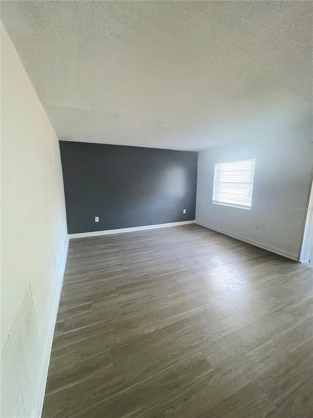 unfurnished room with dark hardwood / wood-style flooring and a textured ceiling