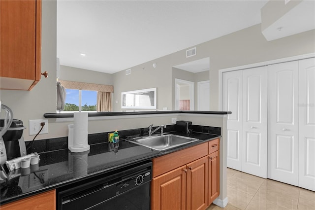 kitchen with dark stone countertops, sink, dishwasher, and light tile floors