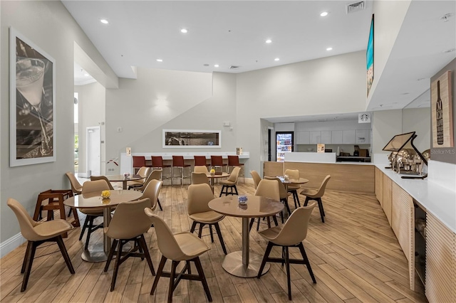 dining area featuring a towering ceiling and light wood-type flooring