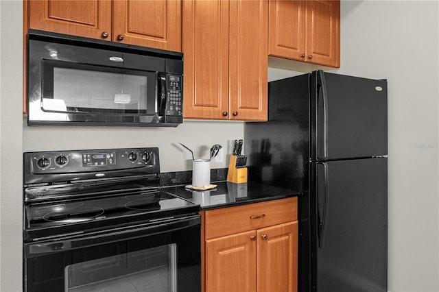 kitchen featuring dark stone countertops and black appliances