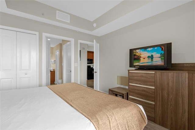 bedroom with a raised ceiling, a closet, and hardwood / wood-style floors