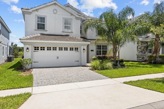 view of front of house featuring a front yard, a garage, and central AC