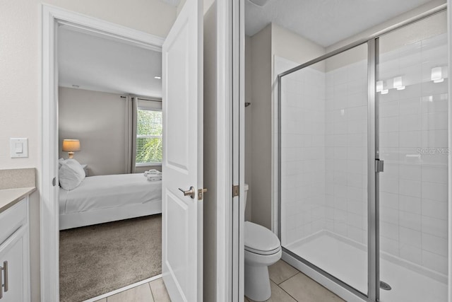 bathroom with a shower with door, tile flooring, vanity, and toilet