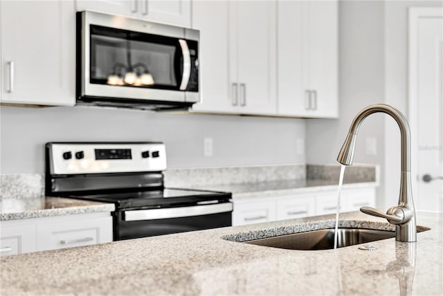 kitchen featuring sink, stainless steel appliances, white cabinets, and light stone counters