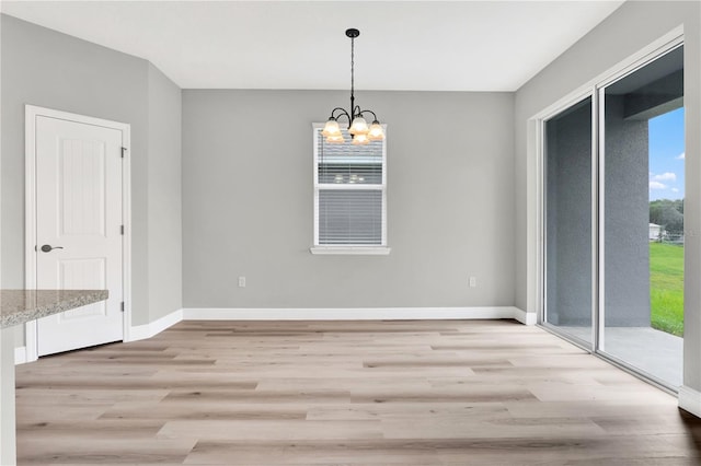 unfurnished dining area featuring an inviting chandelier and light hardwood / wood-style flooring