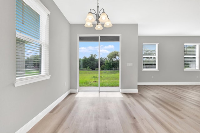 unfurnished dining area featuring light wood-type flooring and an inviting chandelier