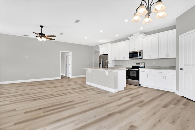 kitchen featuring hanging light fixtures, an island with sink, stainless steel appliances, and white cabinets