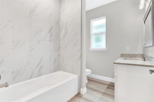 full bathroom featuring hardwood / wood-style flooring, vanity, tiled shower / bath, and toilet