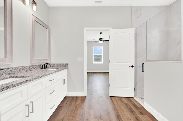 bathroom featuring an enclosed shower, dual bowl vanity, ceiling fan, and hardwood / wood-style floors