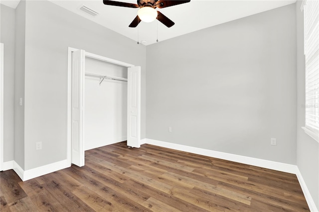 unfurnished bedroom featuring ceiling fan, a closet, and dark wood-type flooring