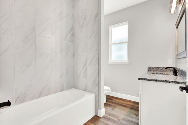 full bathroom with tiled shower / bath, wood-type flooring, vanity, and toilet