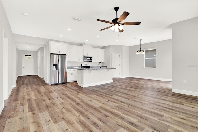 kitchen featuring appliances with stainless steel finishes, white cabinetry, a kitchen island with sink, and light wood-type flooring