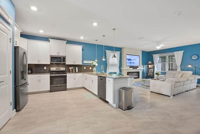 kitchen featuring kitchen peninsula, tasteful backsplash, pendant lighting, white cabinets, and appliances with stainless steel finishes