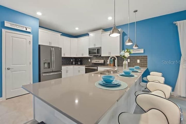 kitchen featuring kitchen peninsula, tasteful backsplash, stainless steel appliances, decorative light fixtures, and white cabinetry