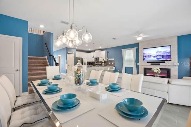 tiled dining space with ceiling fan with notable chandelier