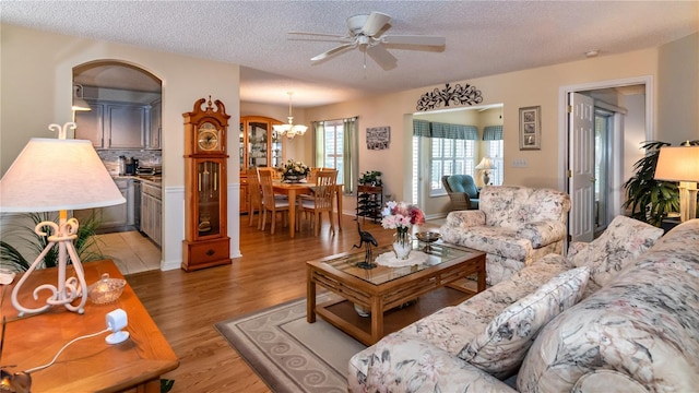 living room featuring tile floors, ceiling fan with notable chandelier, and a textured ceiling