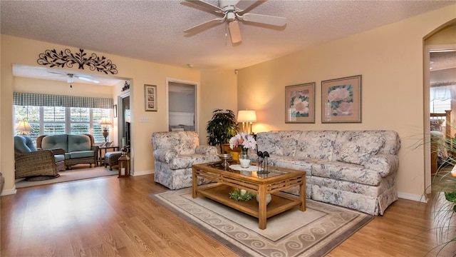 living room featuring ceiling fan, a textured ceiling, and hardwood / wood-style flooring