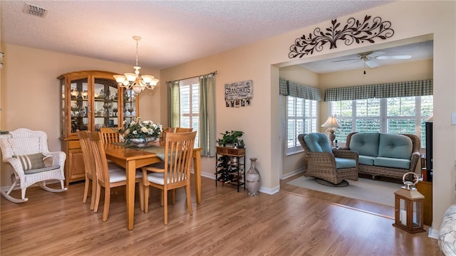 dining area with hardwood / wood-style flooring, a textured ceiling, and ceiling fan with notable chandelier