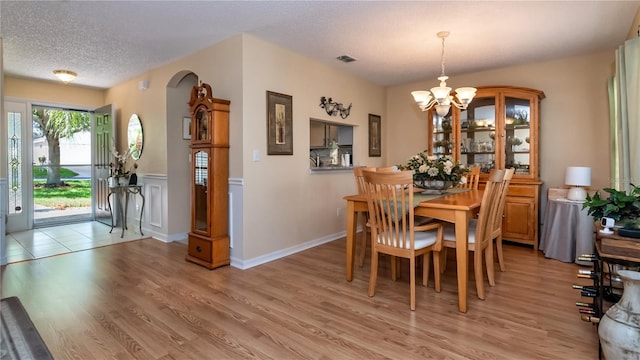 dining space with a notable chandelier, light hardwood / wood-style flooring, and a textured ceiling