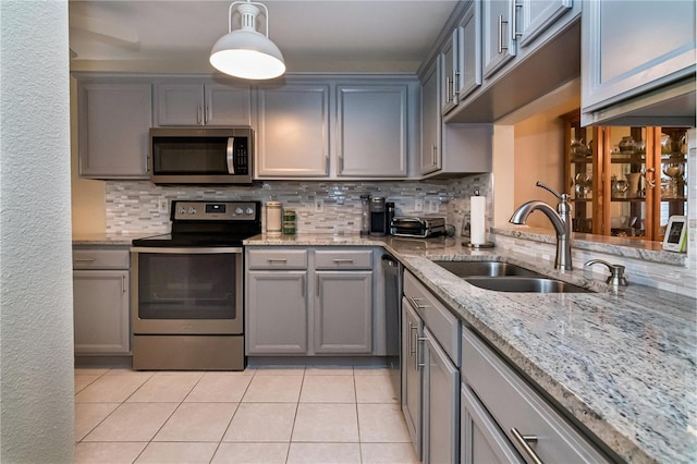 kitchen with decorative light fixtures, backsplash, appliances with stainless steel finishes, sink, and light tile floors