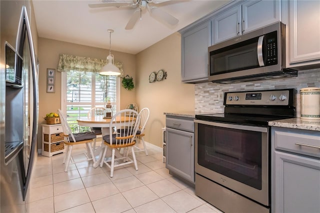 kitchen with stainless steel appliances, light tile floors, light stone counters, and backsplash